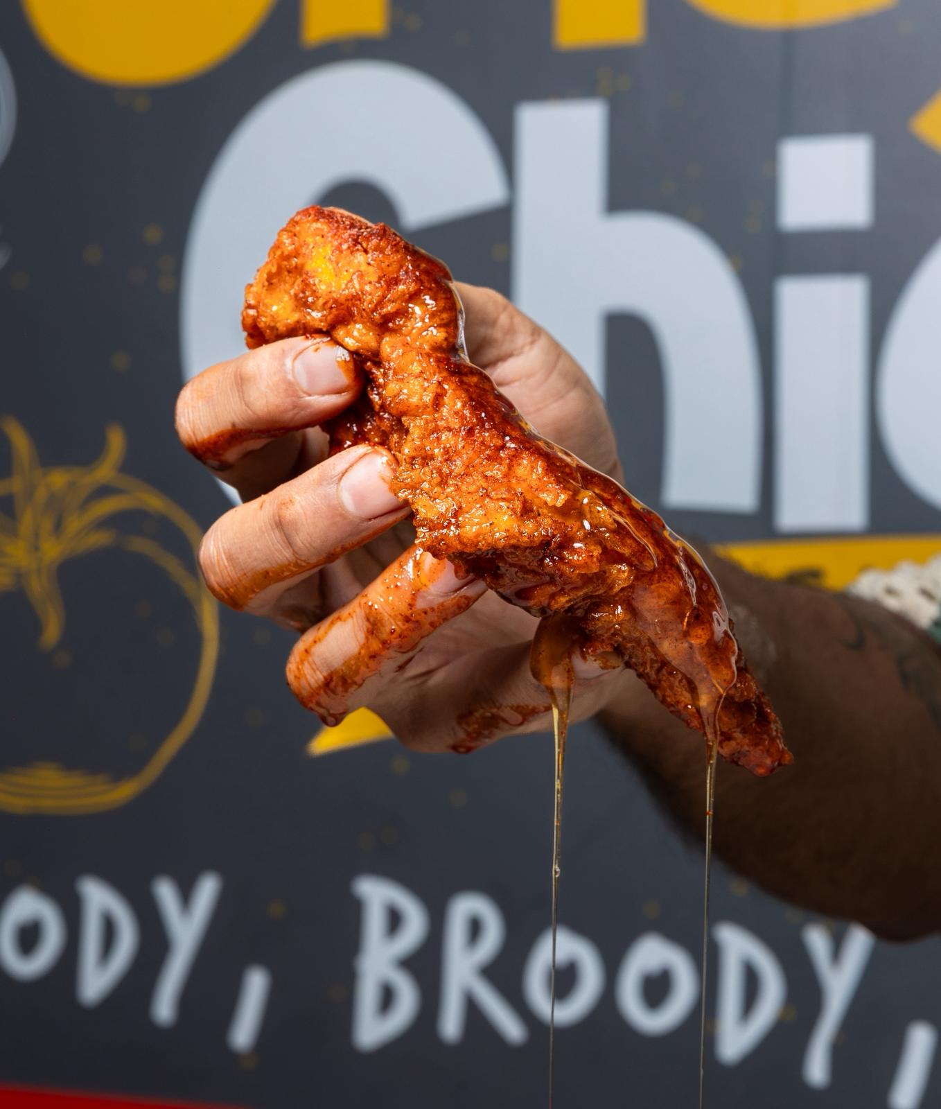Hand holding a hot honey tender at Spicy Chick